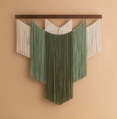 a green and white wall hanging on the side of a beige wall next to a wooden shelf