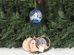 two ornaments hanging from a christmas tree in front of some pine needles and evergreen branches