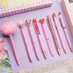 the pink pen is next to other pens and accessories on top of a purple table