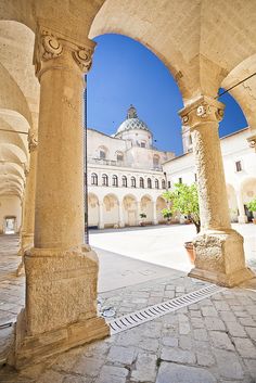 an old building with pillars and arches in front of it, under a blue sky