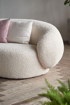 a large white chair sitting on top of a wooden floor next to a potted plant