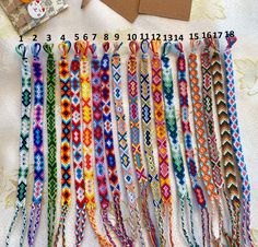 a bunch of colorful bracelets sitting on top of a white bed next to an envelope