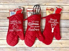 three oven mitts with christmas sayings on them, one is red and the other has