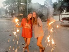 two girls standing in the street holding sparklers