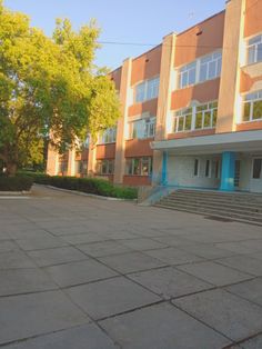 an empty parking lot in front of a building with steps leading up to the entrance