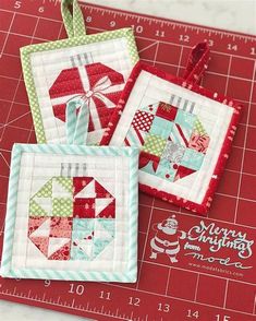 three small quilted christmas ornaments sitting on top of a cutting board