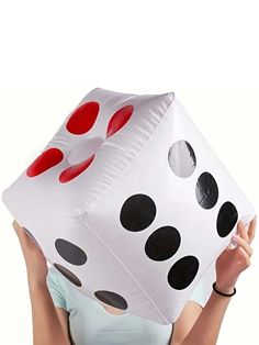 a woman holding up a giant white and black dice shaped balloon in front of her face