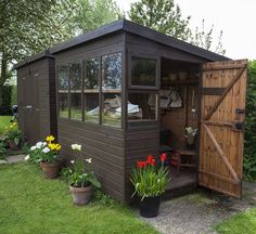 a garden shed with flowers and potted plants