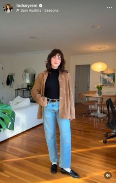 a woman standing in a living room next to a bed