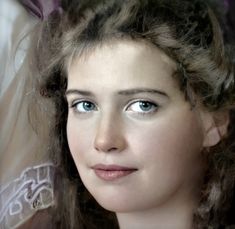 a close up of a woman with blue eyes and hair in a wedding dress looking at the camera