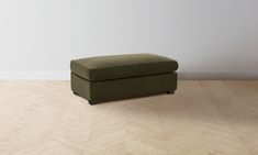 a green ottoman sitting on top of a hard wood floor next to a white wall