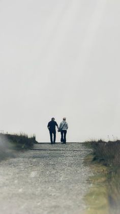 two people walking down a road holding hands