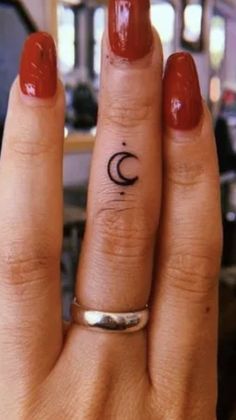 a woman's hand with a small crescent tattoo on her left ring finger,