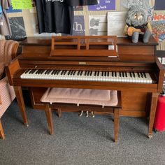 a piano sitting in front of a wall with posters on it's sides and a stuffed animal next to it