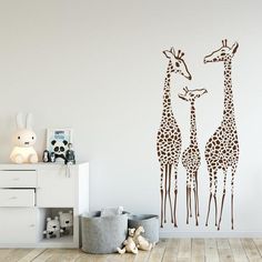 two giraffes standing next to each other on a wall in a room