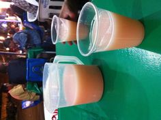 three plastic cups filled with liquid sitting on top of a green table covered in people