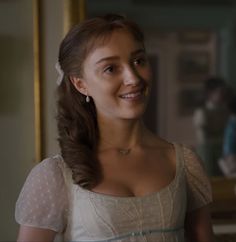 a woman in a white dress is smiling at the camera and she has her hair pulled back