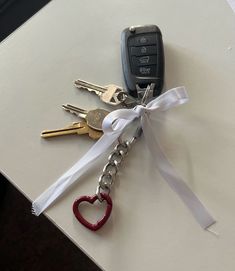 four keys tied together with a white ribbon and a heart shaped keychain attached to them