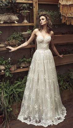 a woman standing in front of plants wearing a dress with flowers on the side and her arms out