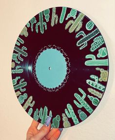 a hand holding up a record that has various designs on it