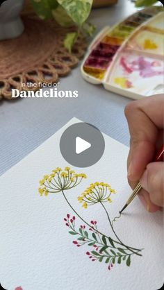 someone is painting flowers with watercolors on paper