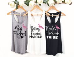 three tank tops hanging on a rack with flowers