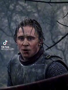 a man with wet hair and armor standing in the woods