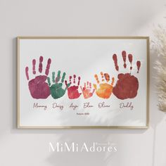 a family handprint is displayed on the wall next to a vase with dried flowers