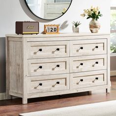 a white dresser with drawers and a mirror