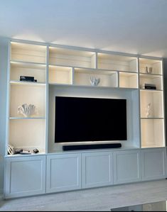 a large entertainment center with white shelves and lights on the wall, along with a flat screen tv