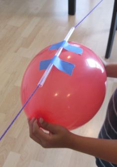 a person holding a red balloon with blue tape on it and a stick sticking out of it