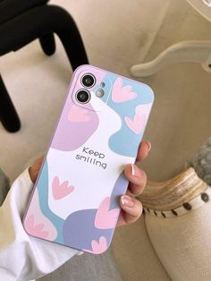 a person holding up a cell phone case with hearts on the back and words keep smiling printed on it