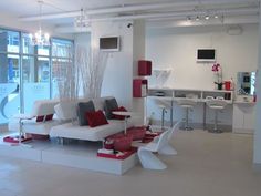 a living room filled with white furniture and red accents