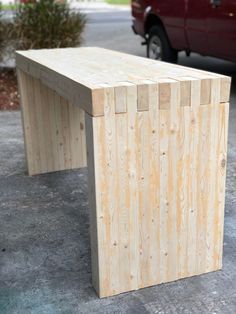 a bench made out of plywood sitting in front of a red truck