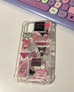 an iphone case with stickers on it next to a keyboard