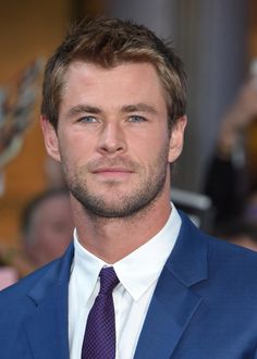 a close up of a person wearing a suit and tie with people in the background