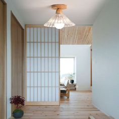 an empty room with wooden floors and white walls, has a light fixture hanging from the ceiling