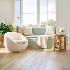 a living room with white walls and wooden floors, a window seat in the corner