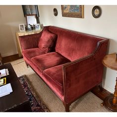 a red couch sitting in the middle of a living room next to a wooden table