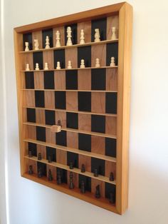 a wooden chess board mounted to the wall with black and white chess pieces on it