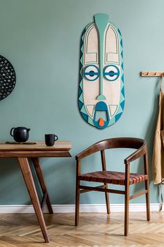 a wooden chair sitting next to a table on top of a hard wood floor under a blue wall