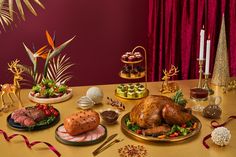 a table topped with lots of different types of food and desserts next to red curtains