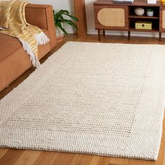 a living room with a brown couch and white rug