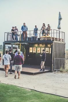 a group of people standing on top of a large container in the middle of a field