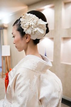 a woman with a flower in her hair wearing a white kimono and red ribbon