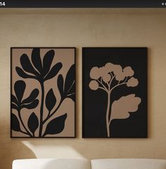 two black and white paintings on the wall above a couch in front of a window