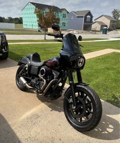 a black motorcycle parked on the side of a road next to some grass and houses