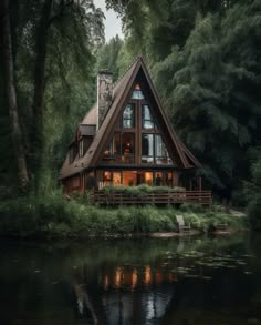 a large house sitting in the middle of a forest next to a body of water