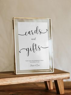 a card and gifts sign sitting on top of a wooden table next to a white wall