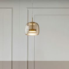 a lamp that is hanging from the ceiling in a room with white walls and flooring